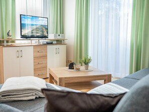 Ein modernes Wohnzimmer mit Fernseher, Couch und Couchtisch aus Holz.