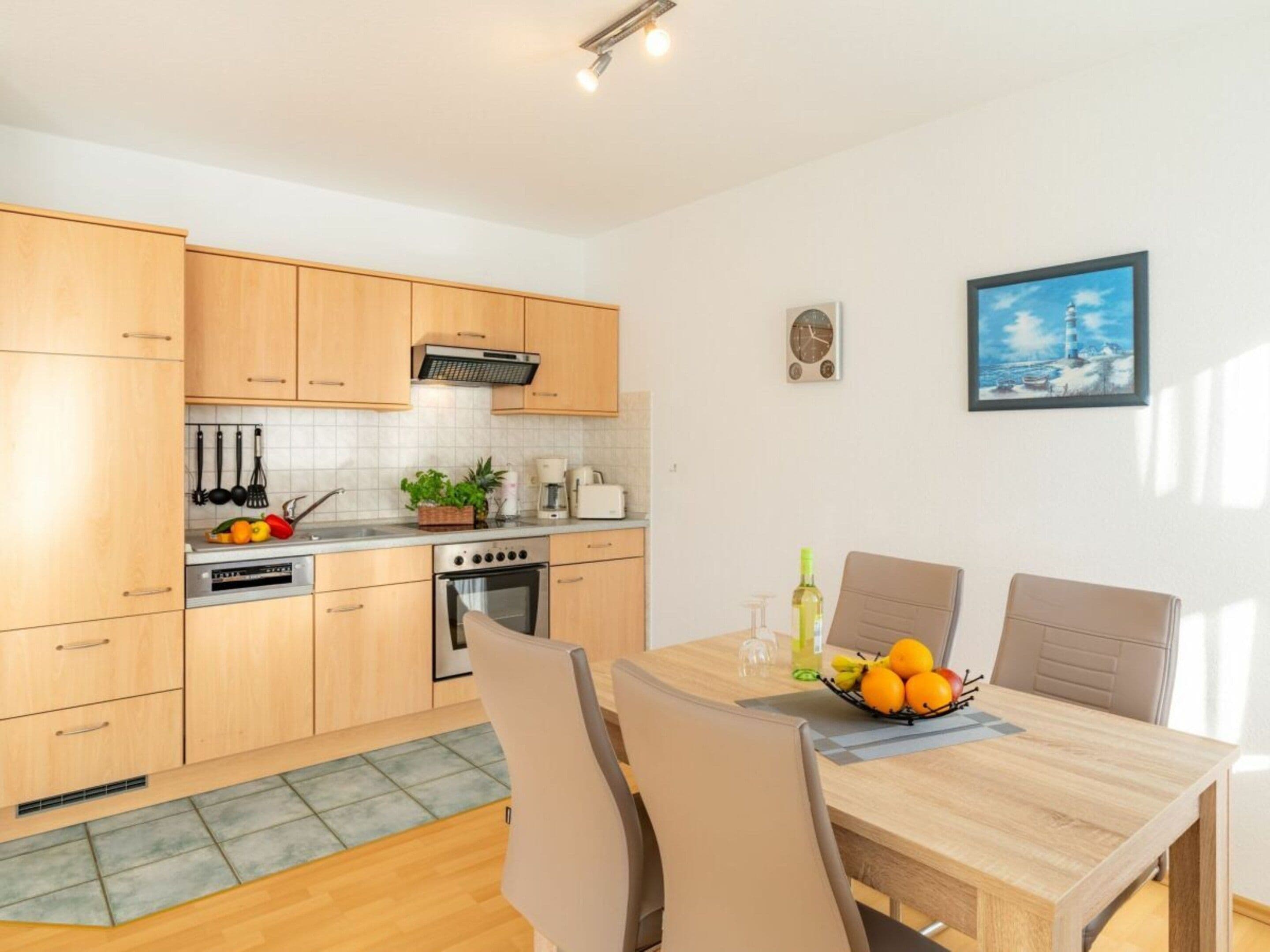 A modern kitchen with wooden cabinets, a built-in oven, and a dining area with a table and chairs.