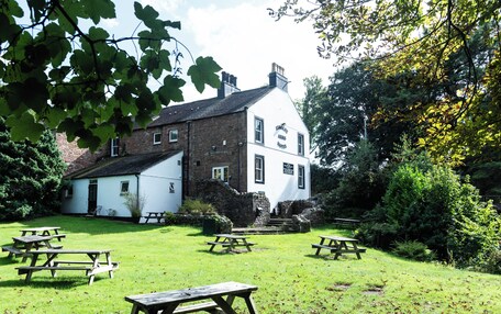 A white building with a sign reading 'Stanley Arms Hotel' surrounded by a grassy area with picnic tables.
