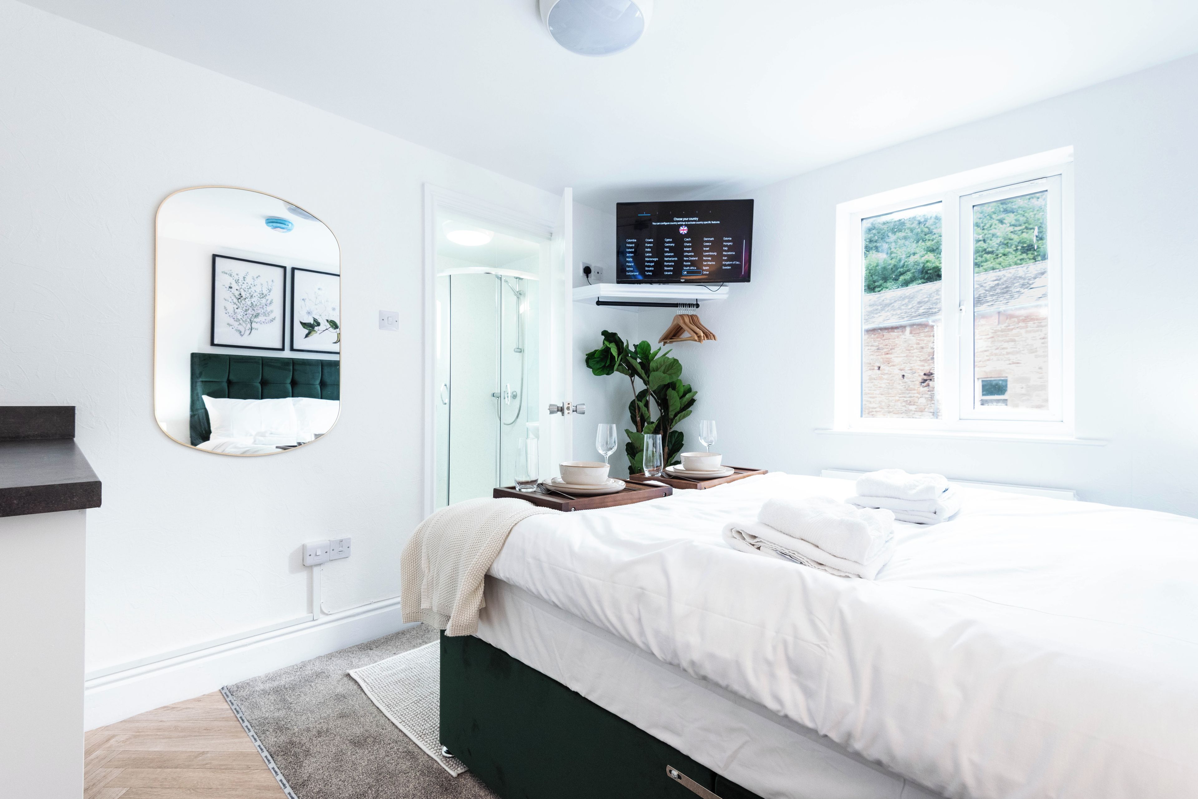 Un dormitorio moderno con una cama, un espejo, un televisor y una ventana.