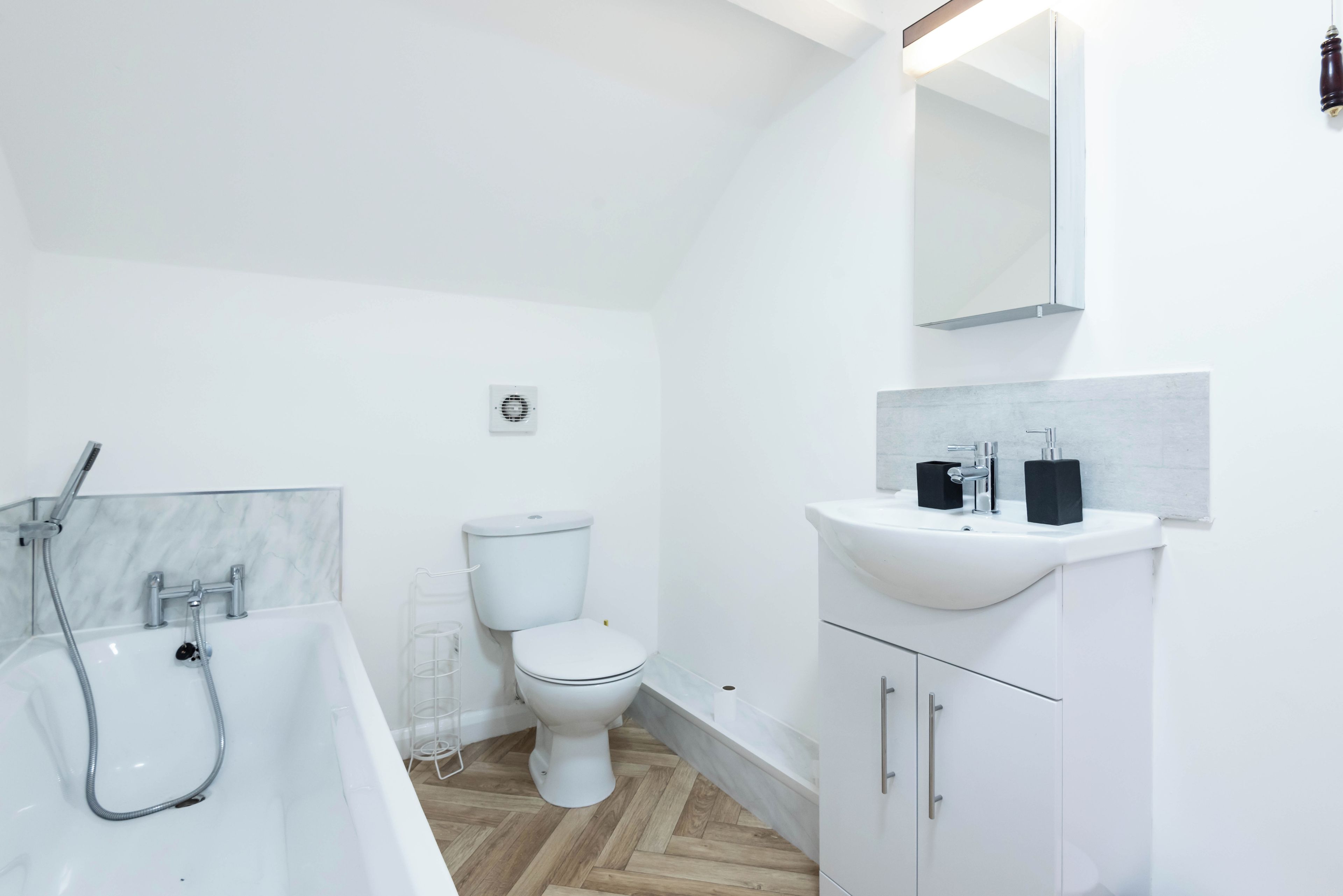 A modern bathroom with a bathtub, toilet, and vanity.