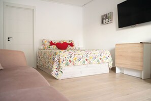A bedroom with a bed, a dresser, a television, and a door. - Costa del Sol Villas - Bedroom with Private Bathroom 4 (Vélez-Málaga)