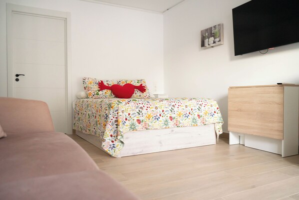 A bedroom with a bed, a dresser, a television, and a door.
