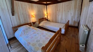 A room with two wooden beds, wooden walls, and a radiator.