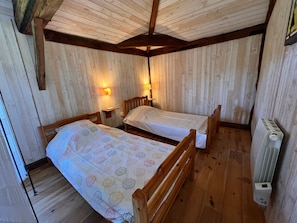 Habitació amb dos llits de fusta, parets de fusta i un radiador.