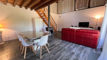 A cozy living space with a dining area, a red sofa, and a wooden staircase.