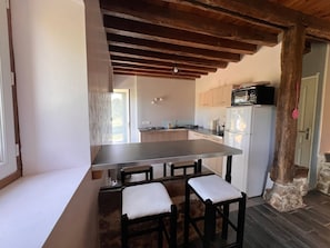 A kitchen with a central island, wooden chairs, a refrigerator, and cabinets.