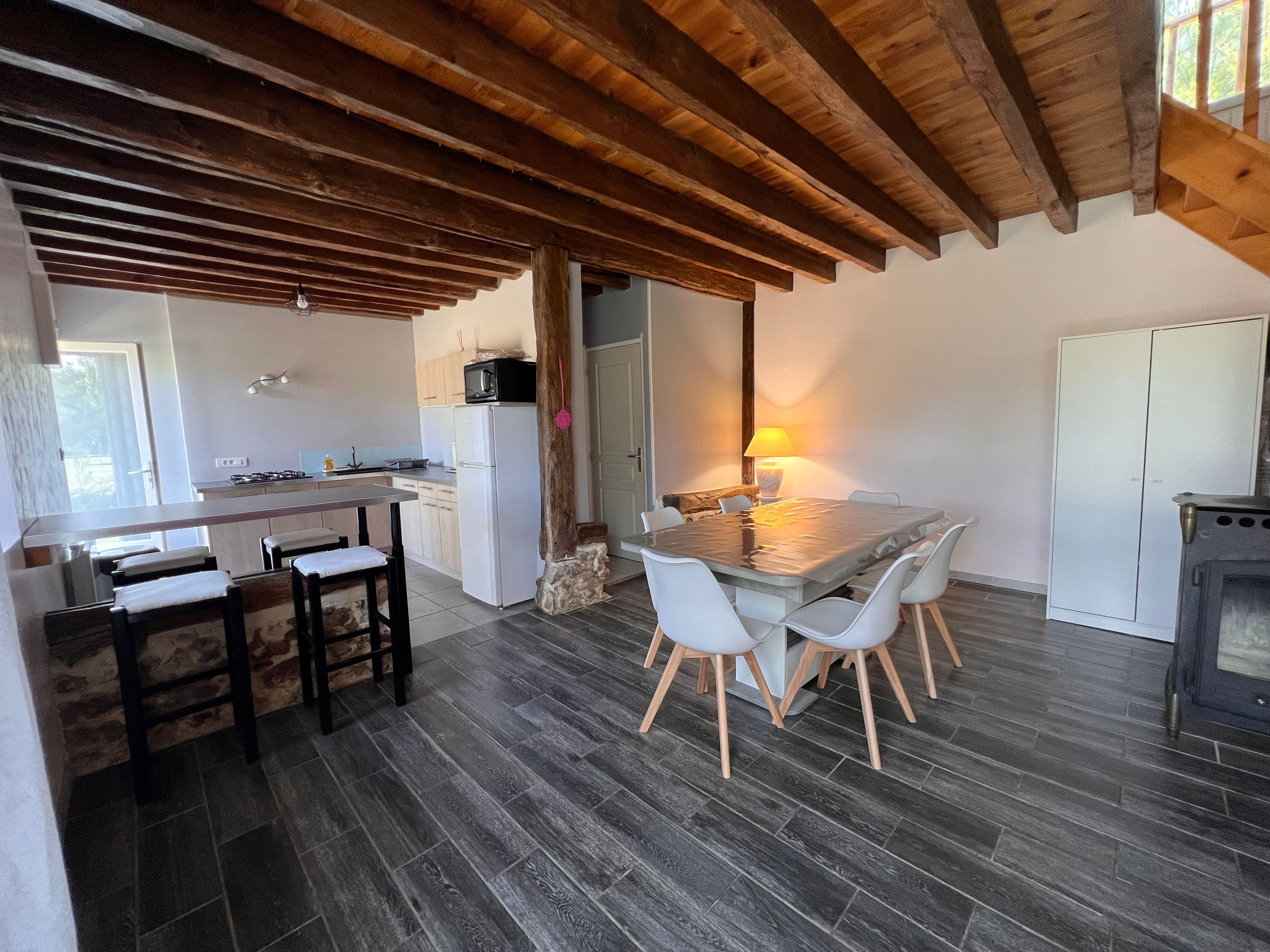 Une cuisine avec un plafond en bois, une table à manger avec des chaises et un poêle.