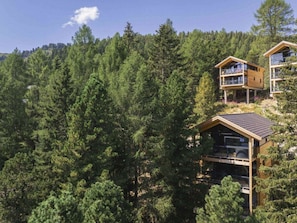A modern wooden cabin with a balcony, surrounded by dense forest. - Superior Chalet #15 With Sauna & Hot Tub (Stadl-Predlitz)