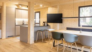 A modern interior with a wooden floor, a kitchen area, and a dining space with chairs and a table. - Superior Chalet #15 With Sauna & Hot Tub (Stadl-Predlitz)
