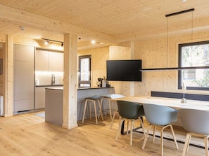 A modern interior with a wooden floor, a kitchen area, and a dining space with chairs and a table. - Superior Chalet #15 With Sauna & Hot Tub (Stadl-Predlitz)