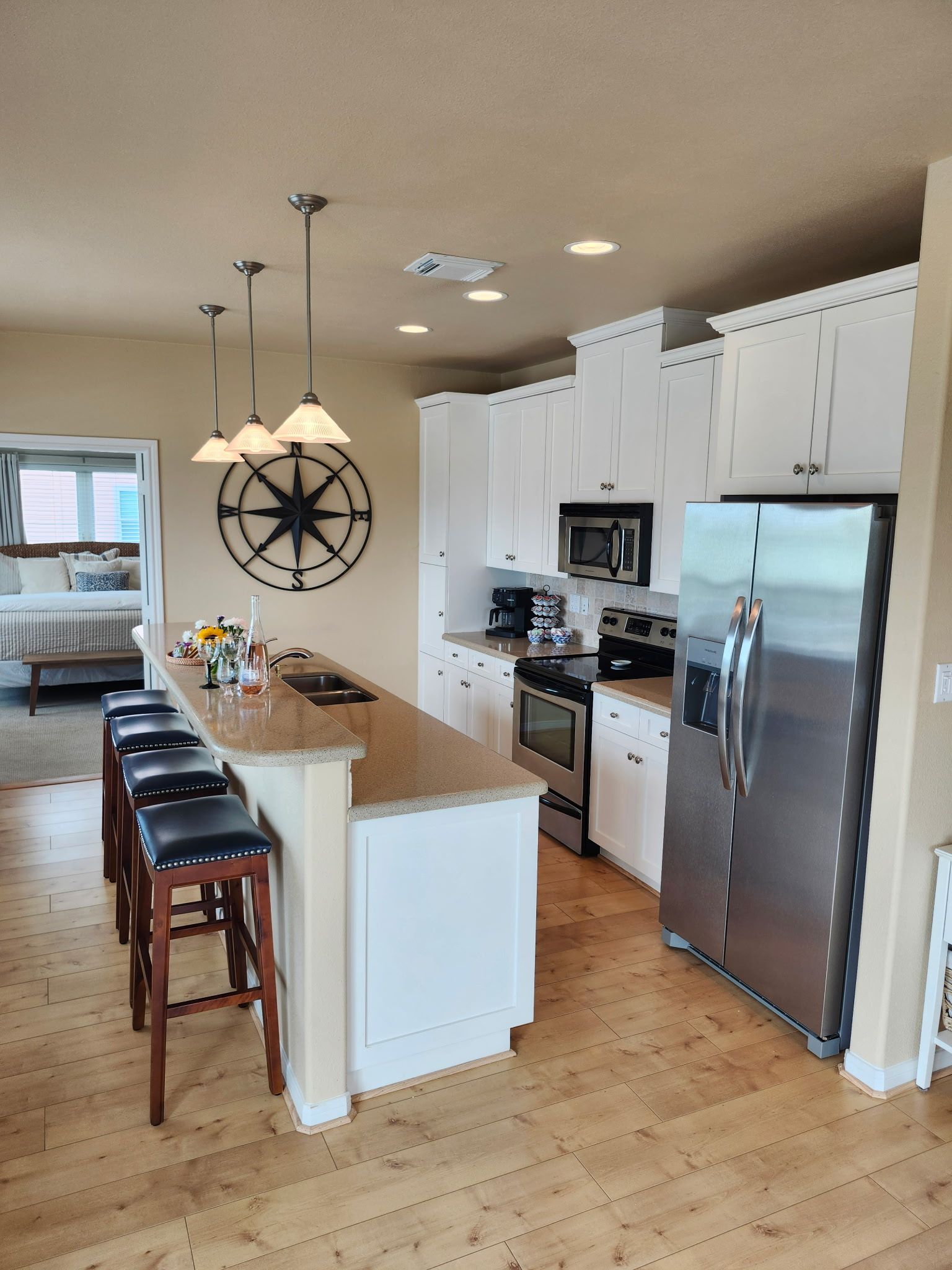 A modern kitchen with white cabinets, stainless steel appliances, and a central island with bar stools.