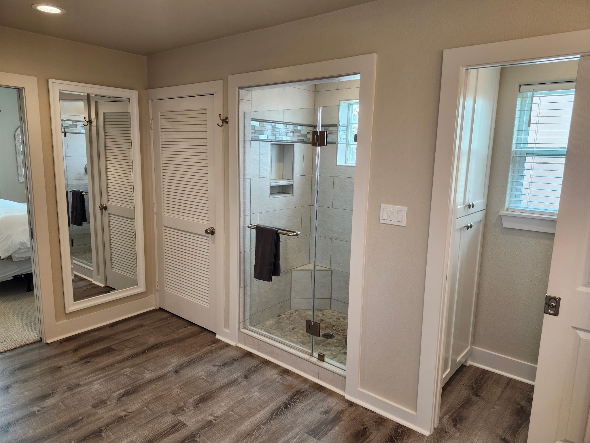 A hotel room with a shower, a bed, and a bathroom with a glass door.
