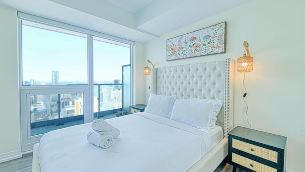 Quarto de hotel com uma cama grande, vista para a cidade e um objeto decorativo na parede.
