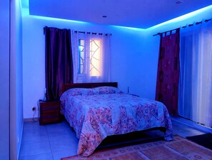 A bedroom with a bed, curtains, a window, and a nightstand.