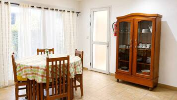 A dining area with a table set for four, a wooden cabinet with glass doors, and a door leading outside.