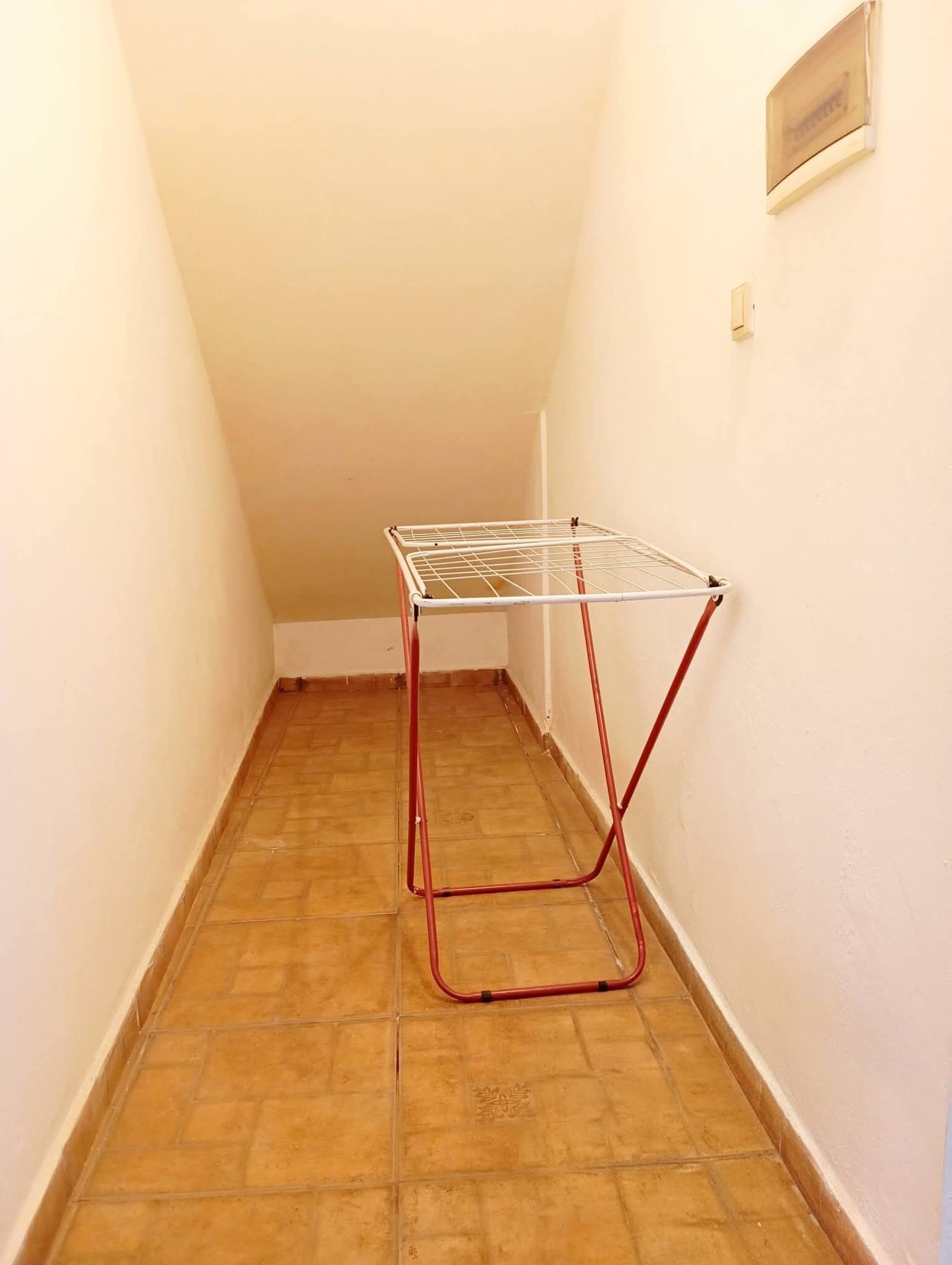 Un couloir étroit dans lequel est fixé au mur un étendoir métallique.