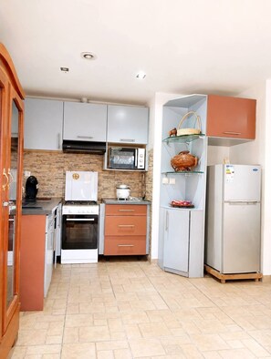 Een kleine keuken met een magnetron, oven en koelkast.