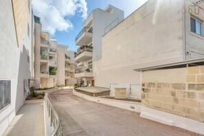 A residential building with multiple balconies, a paved courtyard, and a stone wall. - Siggiewi 3BR Penthouse with Two Terraces & WIFI (Siġġiewi)