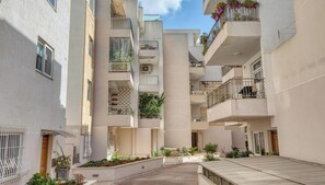 A multi-story residential building with balconies, outdoor plants, and a central courtyard. - Siggiewi 3BR Penthouse with Two Terraces & WIFI (Siġġiewi)