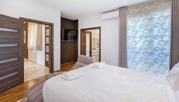 A hotel room with a bed, a TV, a wardrobe, and a bathroom. - Siggiewi 3BR Penthouse with Two Terraces & WIFI (Siġġiewi)
