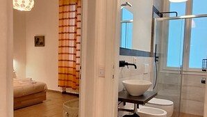 Casa de banho moderna com cabine de chuveiro em vidro, lavatório branco e sanita.