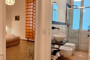 Et stilfuldt badeværelse med brusekabine i glas, en hvid vask og et toilet.