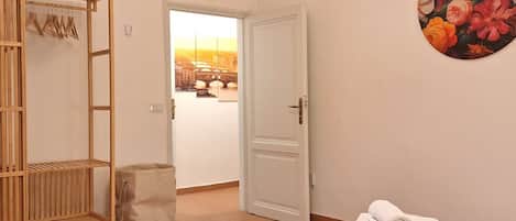 A hotel room with a bed, a wardrobe, a door leading to a balcony, and a painting on the wall.