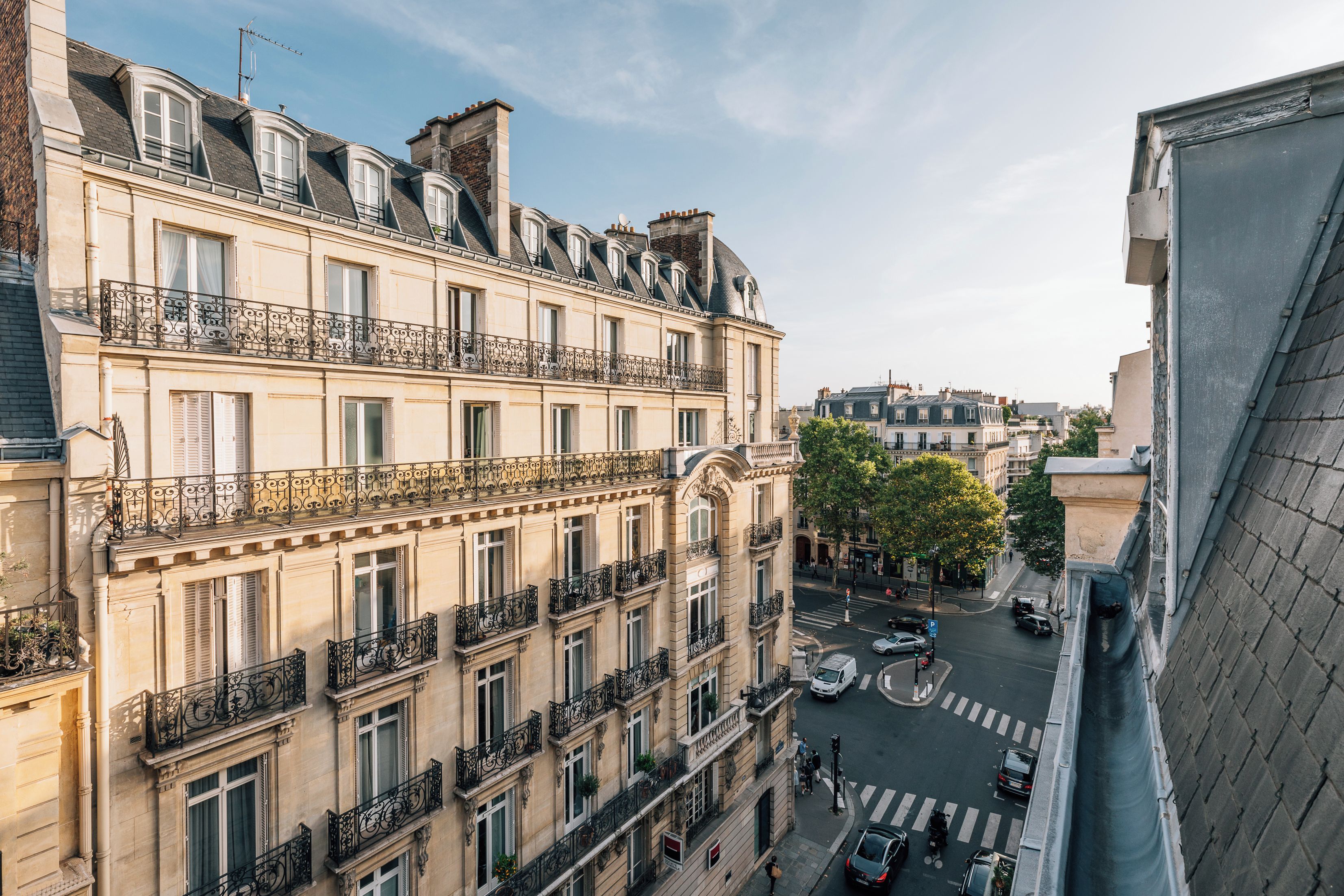 Un edificio de varios pisos con balcones, vista a la calle y cielo despejado.
