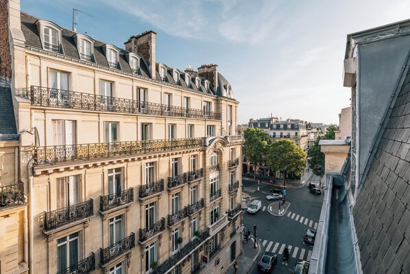 A multi-story building with balconies, a street view, and a clear sky.