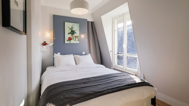 Quarto com cama, janela, pintura e luminária.