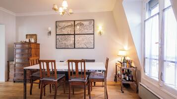 A dining area with a wooden table, chairs, a chandelier, a map artwork, and a wine rack.