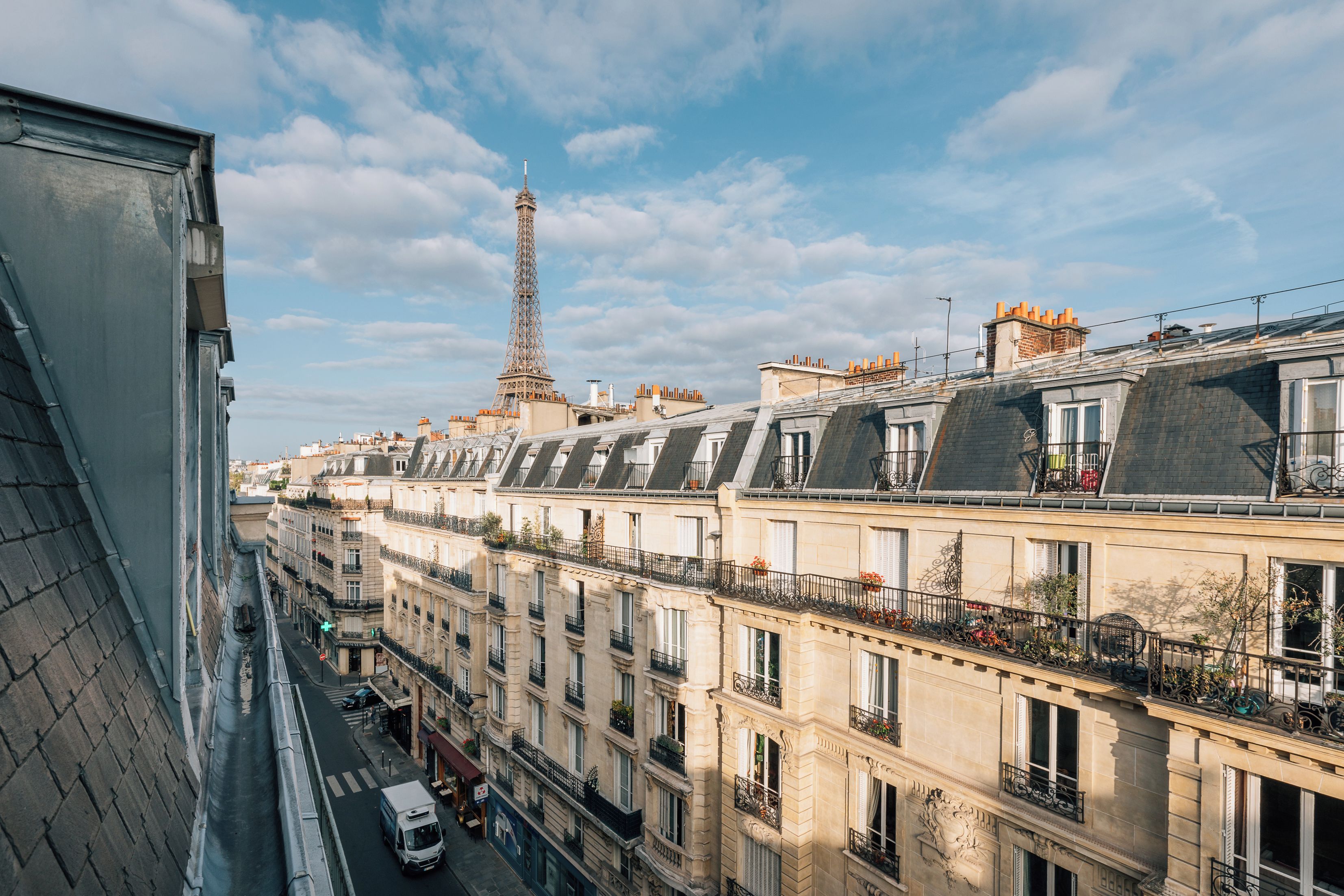 Une rangée de bâtiments parisiens, avec la Tour Eiffel en arrière-plan.