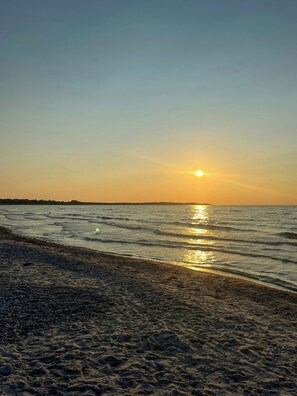A beach with a sunset over the water, sandy shore, and a distant shoreline. - Family summer house with direct beach access (Nykøbing SJ)