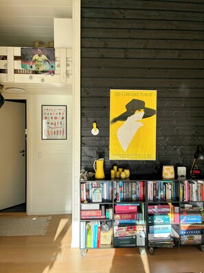 Ein Zimmer mit Bücherregal, einem Poster und einer Tür zu einem Erkerbereich.