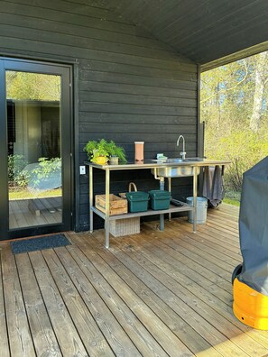 A wooden deck with a built-in kitchen area, including a sink and storage shelves. - Family summer house with direct beach access (Nykøbing SJ)