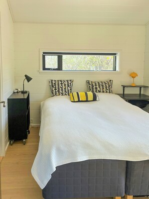 A bedroom with a bed, pillows, a nightstand, a lamp, a window, and a view of trees. - Family summer house with direct beach access (Nykøbing SJ)