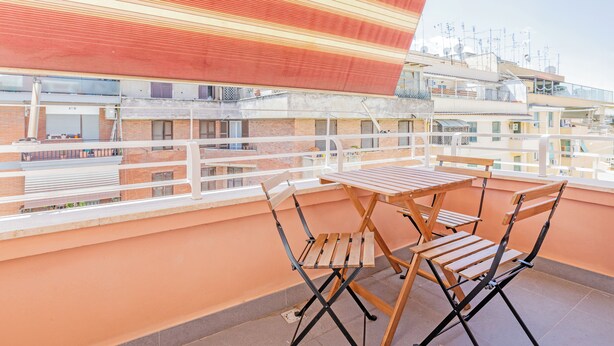 A balcony with a table and chairs, overlooking a residential area with multiple buildings. - Luciano Boutique Apartment (Roma)
