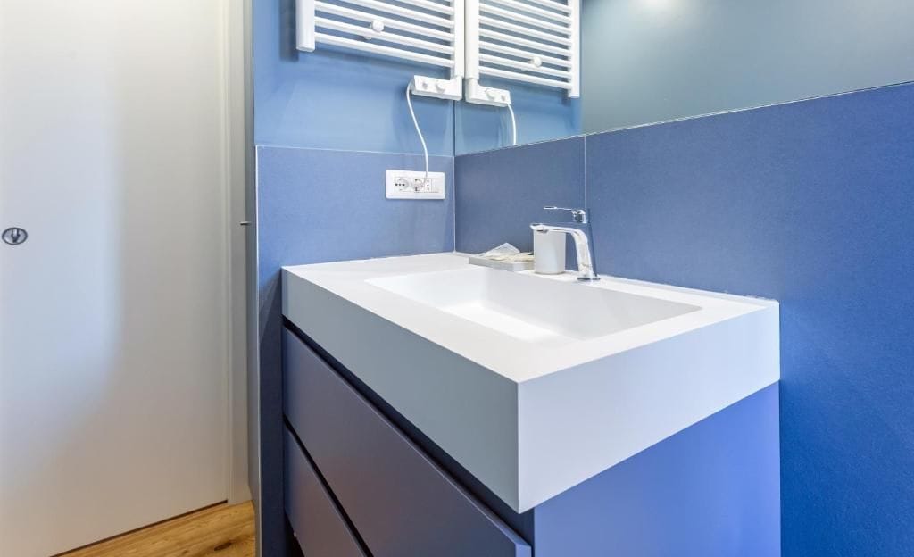 Un baño con un lavabo blanco, un espejo y un perchero para toallas.