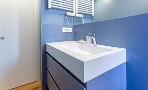 Un baño con un lavabo blanco, un espejo y un perchero para toallas.