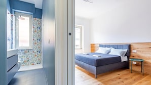 A bedroom with a bed, a bedside table, and a window. - Luciano Boutique Apartment (Roma)