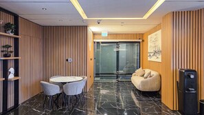 Ein modernes Interieur mit einem runden Tisch und Stühlen, einem Sitzsack, Holzverkleidung und einem Wasserspender.