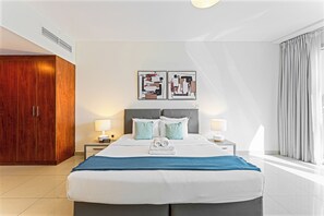 Una camera d'albergo con un letto, due comodini con lampade, un armadio e opere d'arte appese al muro.