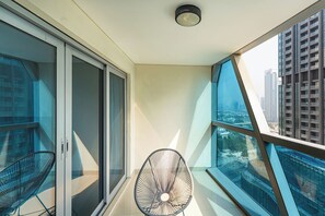 A balcony with a chair, a glass door, and a view of a cityscape. - Amazing 1BR in DIFC | Direct Gate Avenue Access (Dubai)