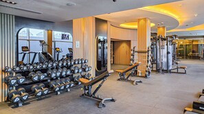 Una palestra con diverse attrezzature per esercizi, tra cui manubri, panche e macchinari per pesi.