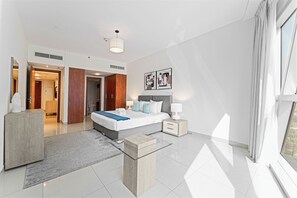Ein modernes Hotelzimmer mit einem großen Bett, Nachttischen, einem Schreibtisch und Blick ins Freie.