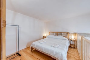 Ein Schlafzimmer mit einem hölzernen Bett, einem Nachttisch, einer Lampe und Holzboden.