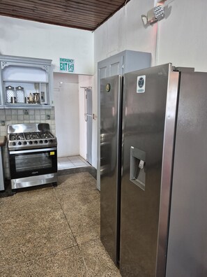 Cuina amb fogó, dos refrigeradors, un rentamics i un senyal d'eixida d'emergència.