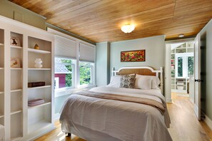 A bedroom with a bed, a bookshelf, a painting, and a view of the outdoors. - Spacious 5-bedroom house with AC, hot tub and space to spread out (Seattle)