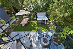 A patio with a hot tub, outdoor seating, and a table with chairs. - Spacious 5-bedroom house with AC, hot tub and space to spread out (Seattle)